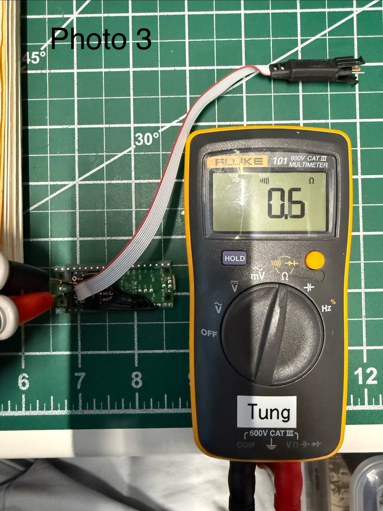 Cable plugged into the breakout, meter probes on the two GND holes — beep
